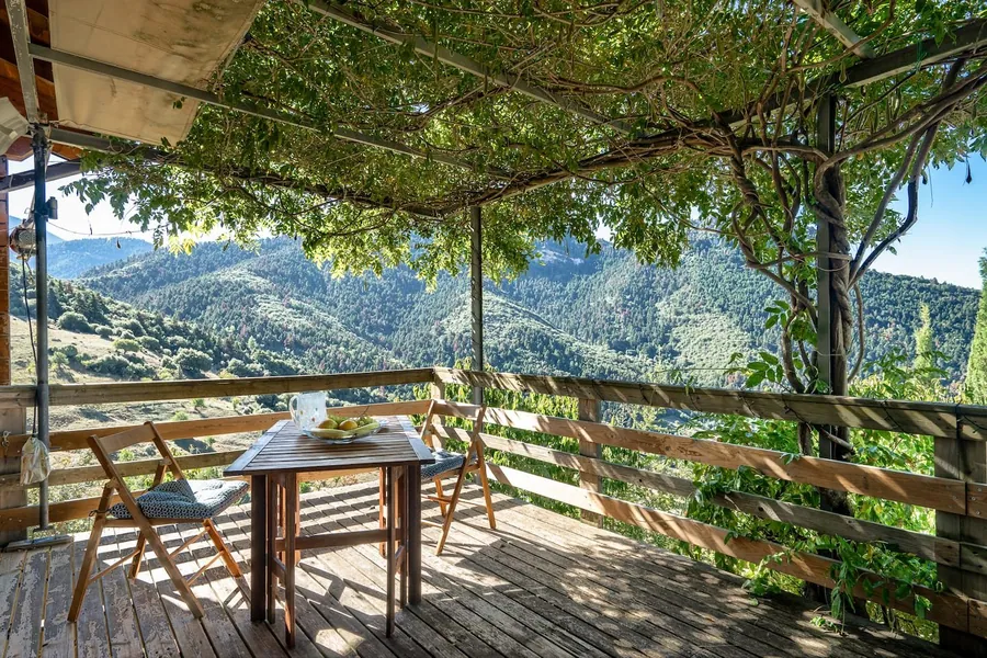 Τραπέζι στη βεράντα κάτω από την κληματαριά, πάνω από την κοιλάδα